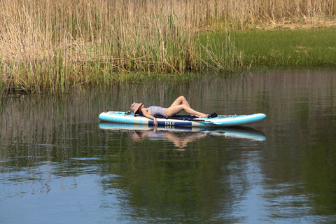 a woman laying on the switch inflatable kayak paddle board hybrid
